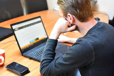 Man using laptop while sitting on table