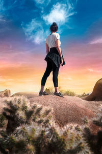 Rear view of man standing on field against sky during sunset