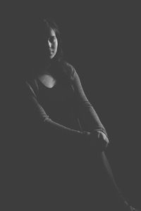 Close-up of young woman standing against black background