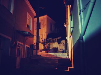 Narrow street amidst buildings in city at night