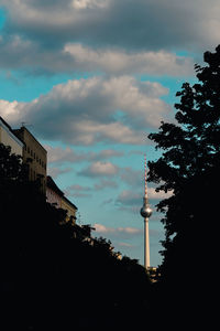 Low angle view of communications tower against cloudy sky