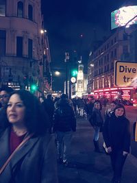 Woman standing on illuminated city street at night