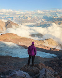 Rear view of man looking at mountains against sky