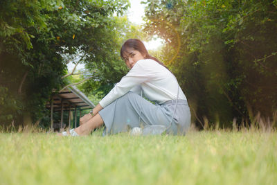 Side view of woman sitting on field