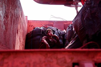 Low angle view of male worker sitting in garbage truck