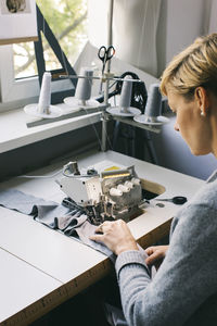 Woman using sewing machine on table in studio