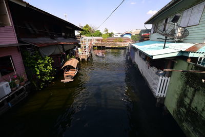 Canal amidst houses against sky