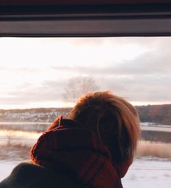 Rear view of woman looking at river during sunset