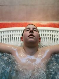 High angle view of boy with eyes closed relaxing in bathtub