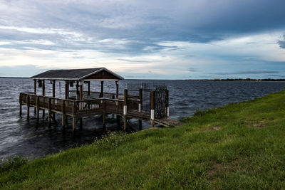 Gazebo on sea against cloudy sky