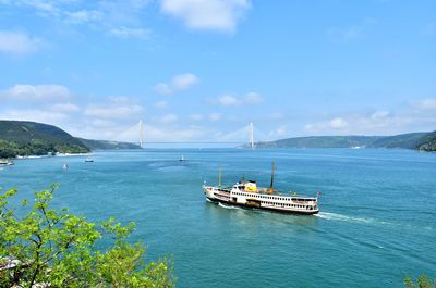 Bridge and ferry over the sea against the sky