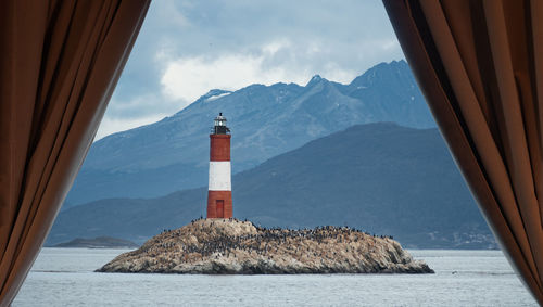 Lighthouse by sea against sky