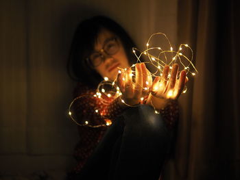 Close-up of woman holding illuminated lighting equipment
