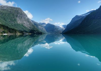 Scenic view of lake and mountains against blue sky