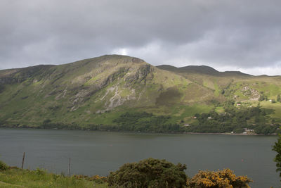 Scenic view of lake and mountains against cloudy sky