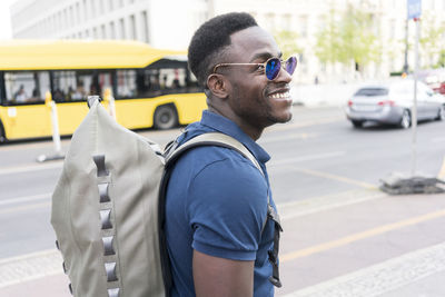 Happy man with backpack walking on footpath