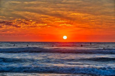 Scenic view of sea against dramatic sky during sunset