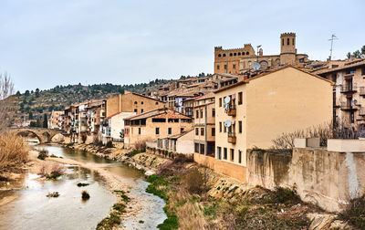 River by residential buildings against sky