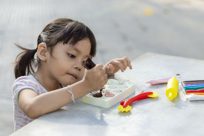 Close-up of cute girl playing with childs play clay at table outdoors