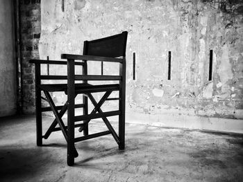 Empty chairs and table against wall in old building