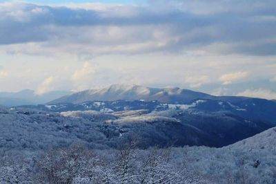 Snow covered mountains against cloudy sky