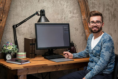 Portrait of young man using laptop at table