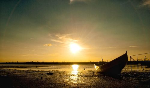 Abandoned boat at beach against sky during sunset