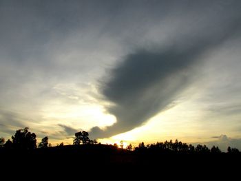 Low angle view of silhouette trees against dramatic sky