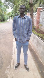 Full length portrait of young man standing against trees