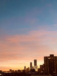 Modern buildings in city against sky during sunset