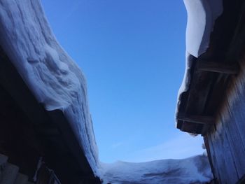 Low angle view of snow covered mountain against blue sky