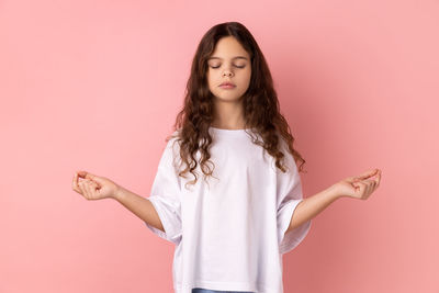 Portrait of young woman against pink wall