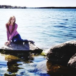 Woman sitting on rock by lake