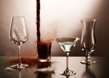 Close-up of ground coffee being poured in glass with drink and feather on table