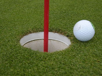 High angle view of golf ball by flag on grass