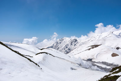 Scenic view of snow covered mountains against blue sky