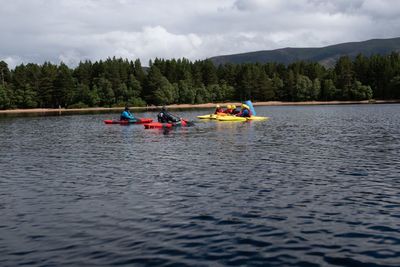 People on boat in river against sky