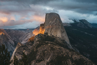 Glowing sunset illuminates the clouds and half dome of yosemite