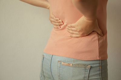 Midsection of woman standing against wall