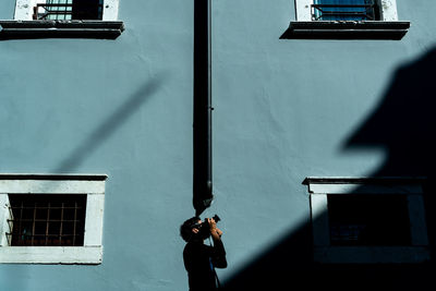 Man photographing against building