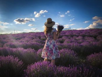 Woman wearing dress and hat in a field of lavender