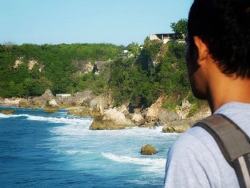 Rear view of man photographing sea against clear sky