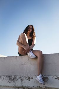 Low angle view of woman sitting against wall