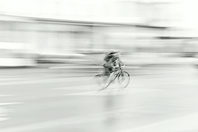 Blurred motion of person riding bicycle on street