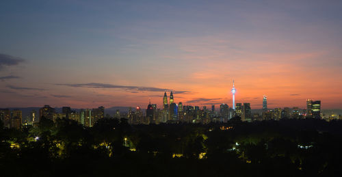 Illuminated city against sky at sunset