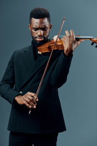 Man playing violin while standing against white background