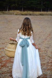 Rear view of girl with wicker basket walking outdoors