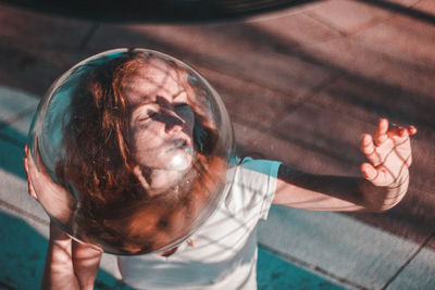 Close-up high angle view of young woman wearing glass helmet in head during sunny day