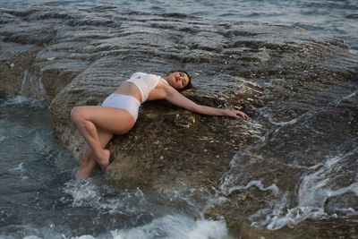 High angle view of young woman on rock at sea