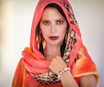 Portrait of beautiful young woman standing against wall